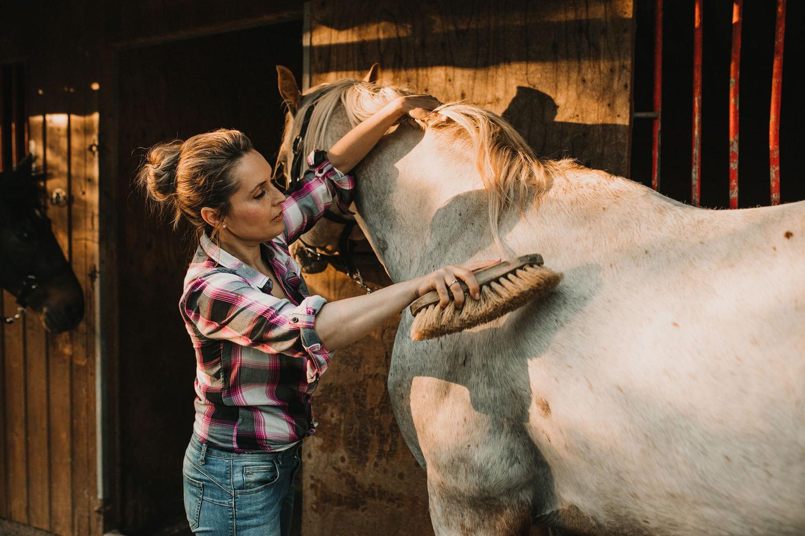 Raquel cepillando a un caballo en el establo